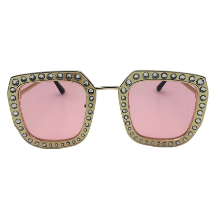 Sunglasses with pink lenses and decorative frame on a light gray background