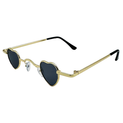 Heart-shaped sunglasses with gold frame and black lenses on a light gray background