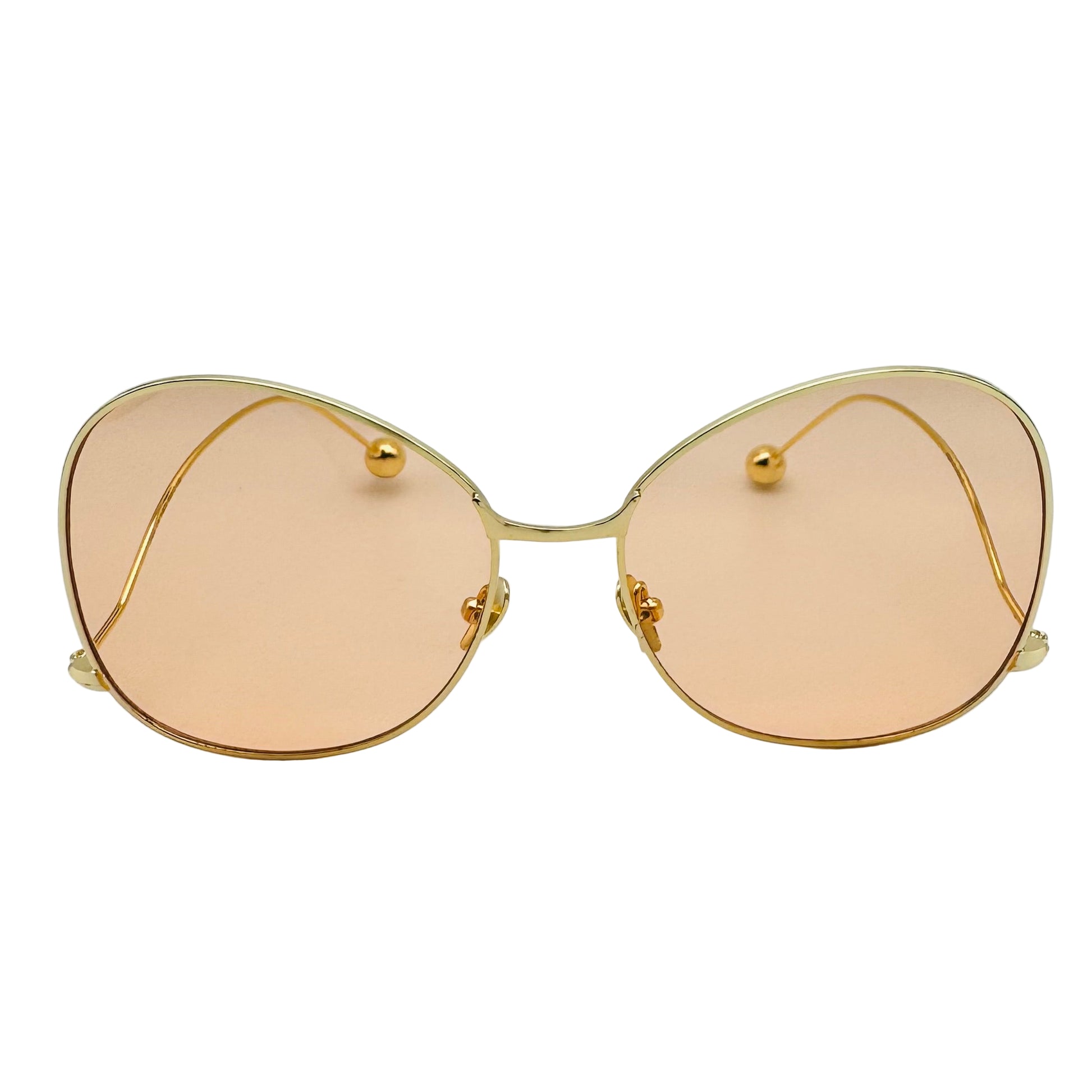 Gold-framed sunglasses with peach-tinted lenses on a white background