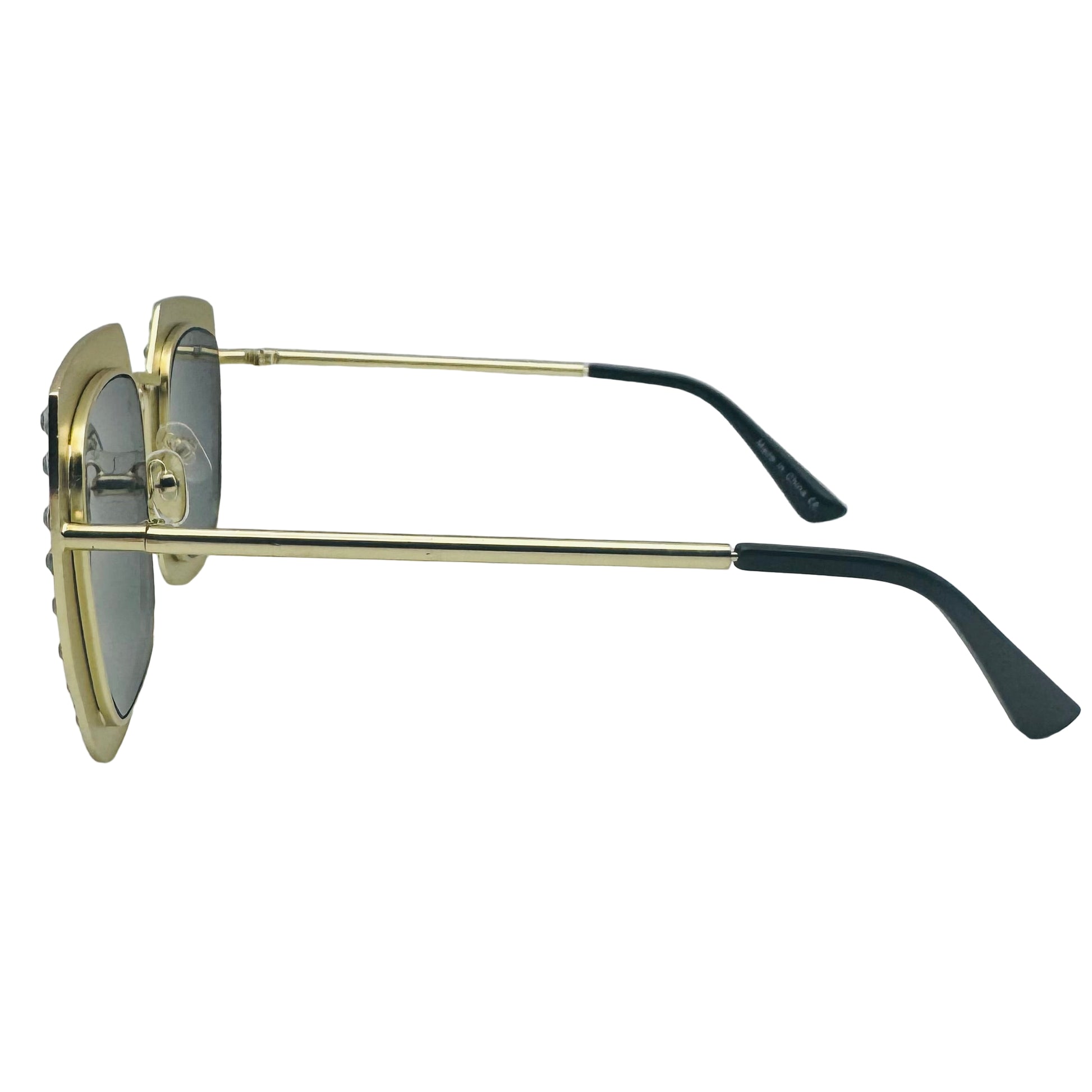 Sunglasses with gold frame and black arms on a light gray background