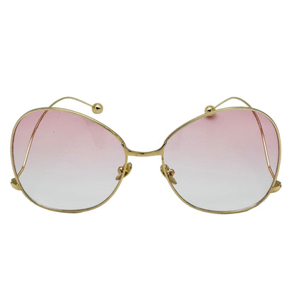Gold-framed sunglasses with pink gradient lenses on a white background