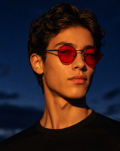 Model wearing the 5009 Echo classic round wire frame sunglasses in Black/Red, showing the slim black metal rims, keyhole bridge, and red tinted lenses